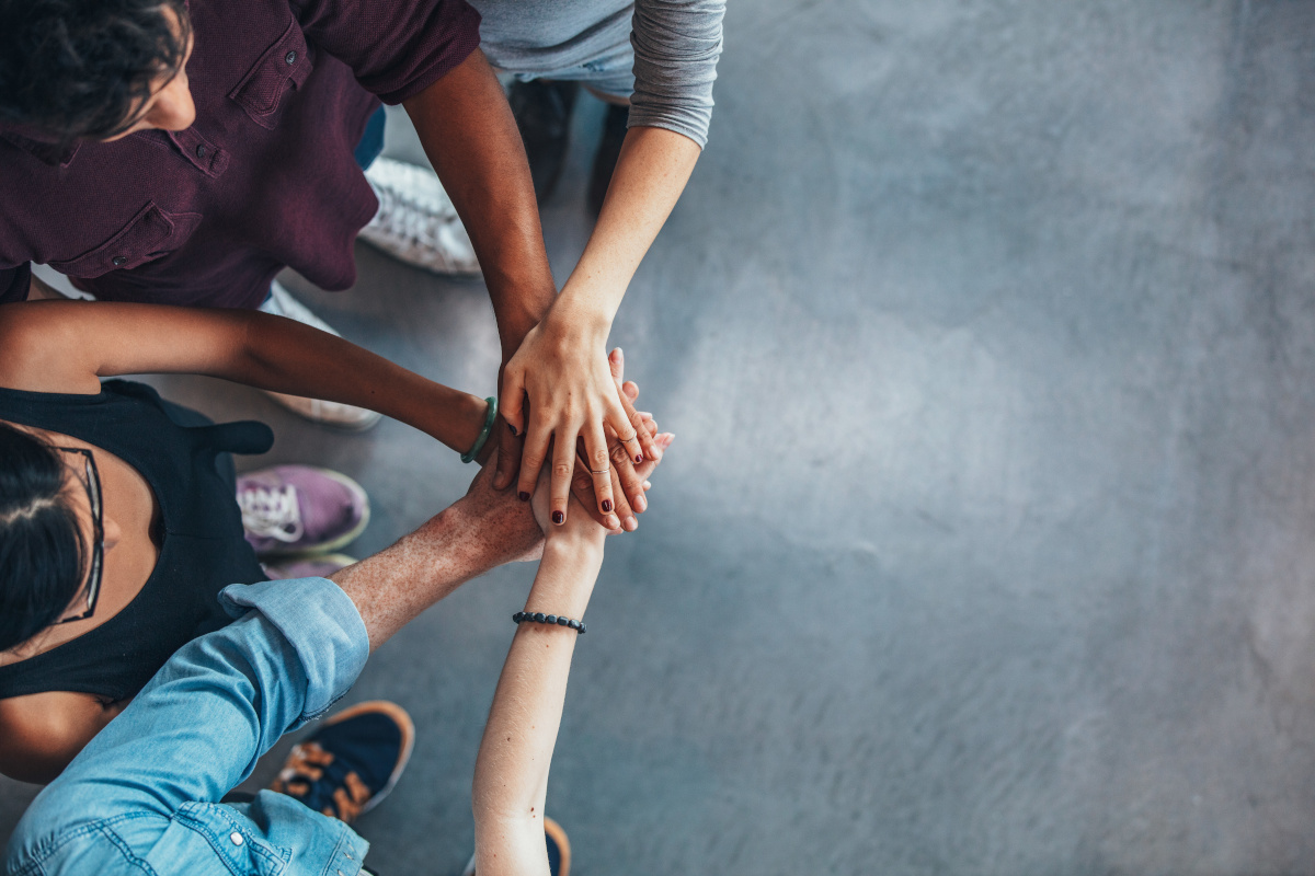 Top view image of group of young people putting their hands together. Friends with stack of hands showing unity.