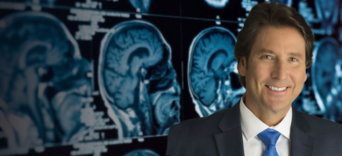 Dr. Perry Mansfield standing in front of an wall of skull x-rays